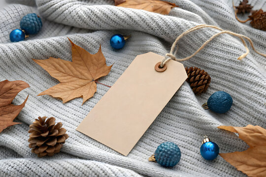 Blank kraft tag on knitted gray sweater with autumnal decor