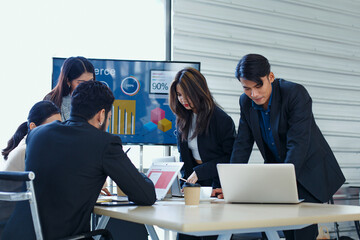 Diverse business team analyzing market trends in modern office with digital screen presentation showing sales data and strategy charts for e-commerce growth.
