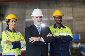 A foreman and worker are standing in a factory, looking standing pose. They wear a yellow and white...