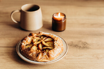 Appetizing homemade peach galette on wooden kitchen table.