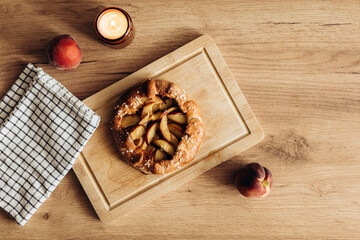 Appetizing homemade peach galette on wooden kitchen table.