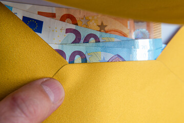 Man's hand in an envelope giving euro money as a bribe.