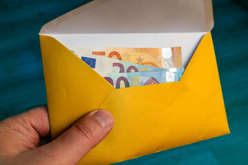 Man's hand in an envelope giving euro money as a bribe.