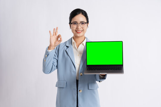 Enthusiastic professional shows laptop with green screen making okay gesture against white backdrop - Powered by Adobe