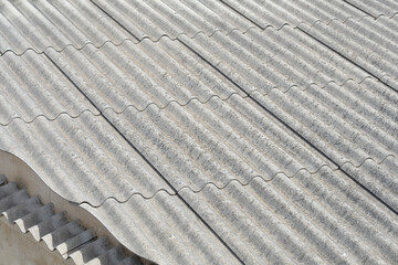 A close-up view of an old, weathered corrugated asbestos cement roof with a wavy pattern © nahhan