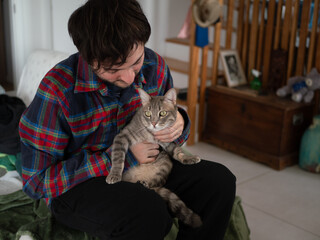 Ma&icirc;tre tenant son chat sur les genoux dans le salon, moment de complicit&eacute;