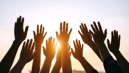 Silhouettes of many hands raised in the air at sunset