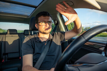 Driver shielding eyes. Sun glare in car. Highway journey.