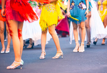 Close-up of women's legs in colorful carnival costumes at the Nha Trang Marine Festival carnival. Shiny fabrics, feathers, heels, movement, festive atmosphere. selective focus