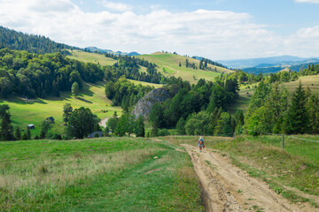An active senior woman is seen walking alone along a scenic forest path surrounded by lush greenery...