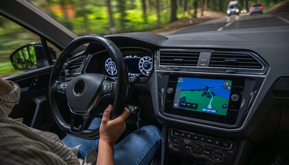 Female driver steering car. Driving forest road. Navigation display