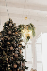 Decorated Christmas tree under a beautiful chandelier in a bright indoor space during holiday season