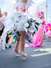 Crop photo of participant in white carnival dress with fluffy skirt and high heels, back view, at street parade in honor of Marine Festival in Nha Trang, Festive atmosphere, crowd.