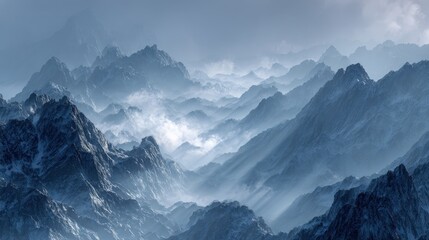 Obraz premium Misty blue mountain range with sharp peaks emerging through clouds under a soft, cloudy sky.