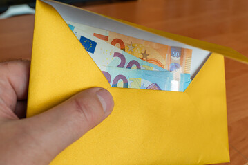 Man's hand in an envelope giving euro money as a bribe.