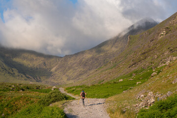 Loneliness on the path, female hiker walks towards mountain summit