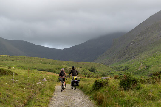 Cycle touring and bikepacking in Ireland, a couple on a rocky path in the Kerry Mountains. Irish Bank Holiday cycling, fresh air, relaxation, and peace in the mountains.