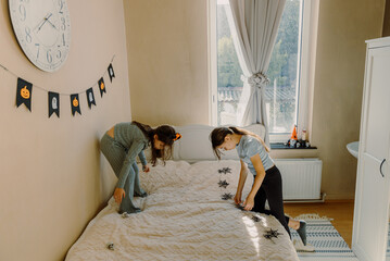 Two little girls are preparing to hang Halloween flags on the wall.