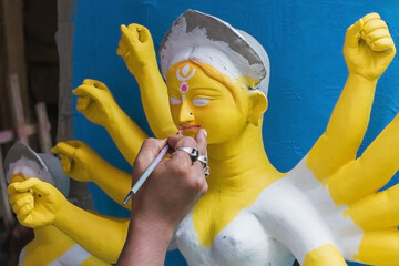 An artist in Kumartuli, Kolkata, West Bengal whole-heartedly immersed in sculpting the clay idol of...
