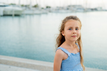 Portrait of a little girl on the seashore in a French town near a yacht marina.