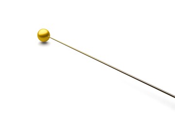 Golden sewing pin with a spherical head lying diagonally on a white surface studio shot