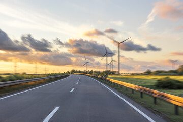 Wind farm along the road. Nature energy at sunset. Motion and technology