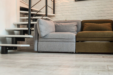 Close-up of a cozy corner in a loft-style living room featuring a grey and olive modular sofa...
