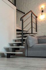 Minimalist staircase with white treads and black metal railing in a modern loft interior, adjacent...