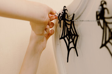 Hands of two sisters hang a Halloween cobweb garland on the bed.