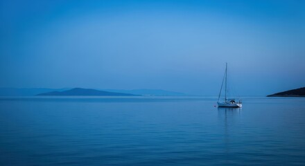 Fototapeta premium Serene twilight seascape featuring a solitary sailboat gently anchored amidst tranquil waters and distant islands.