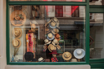 Display window of a hat shop with a variety of straw hats, fedoras, and wide-brimmed styles neatly...