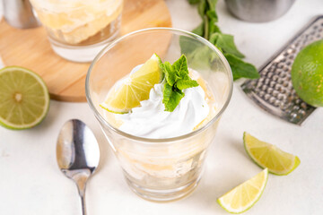 Summer mojito tiramisu dessert, Lime and mint sweet sour taste version of summer tiramisu layered cake with fresh citrus curd, mascarpone and savoyardi. Portion mojito tiramisu parfait dessert