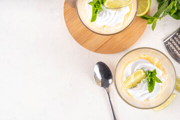Summer mojito tiramisu dessert, Lime and mint sweet sour taste version of summer tiramisu layered cake with fresh citrus curd, mascarpone and savoyardi. Portion mojito tiramisu parfait dessert