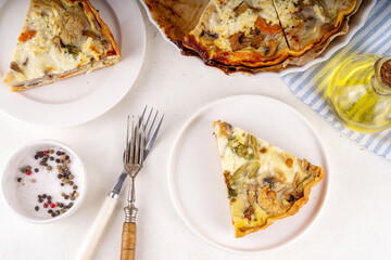 Slice of freshly baked homemade pie quiche lorraine on white table, top view, copy space. Vegan quich tart pie with mushrooms, tomatoes, zucchini, spinach and cheese