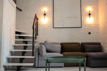 Loft-style living room with a green round coffee table in focus, a modular sofa in neutral colors,...