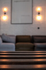 Close-up of a wooden slatted table in focus with a blurred cozy living room in the background. Warm...