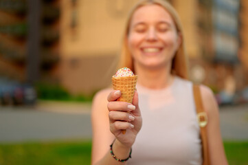 woman holding ice cream cone outdoors, smiling in summer sunlight. ice cream sprinkles, joyful expression, urban background. embracing happiness and summer vibes.