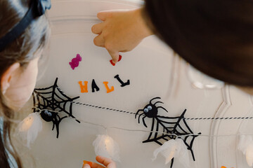 Girls glue jelly candies for Halloween decor on the bed.