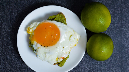 Nutritious breakfast highlighting sunny side up egg crowning creamy guacamole toast, complemented...