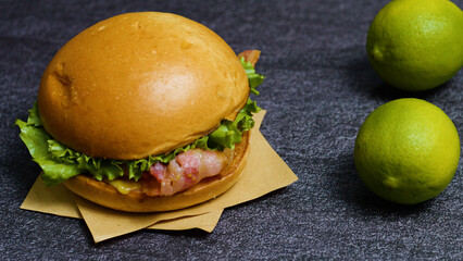 Juicy burger featuring crispy bacon and fresh lettuce sits invitingly on a piece of brown paper,...