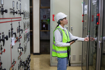 Power station inspection with worker wearing safety helmet and reflective vest checking relay panel...