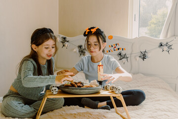 Girls have breakfast with Halloween sweets in bed.