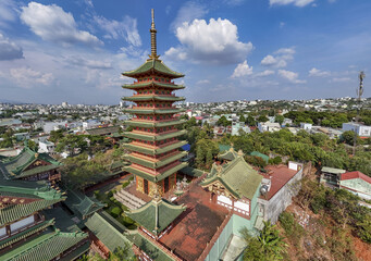 Aerial view of Minh Thanh Pagoda rises with vibrant red and green hues against the city skyline, a testament to architectural grace, Pleiku, Gia Lai, Vietnam.