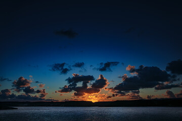 A landscape of a Corsican sunset with clouds and a colorful sky, creating a mystical and...