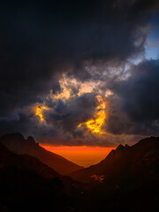 A landscape of a Corsican sunset with clouds and a colorful sky, creating a mystical and captivating atmosphere. The contrasts between moonlight and cloud shadows add a dramatic touch.
