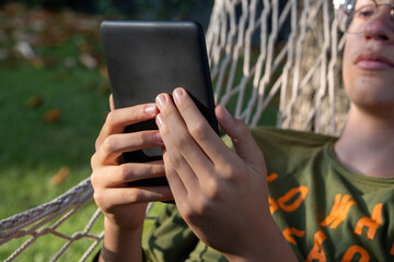 Close-up of hands holding an e-reader, a technology mockup. Teenager using a digital tablet device...