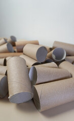 Cardboard sleeves on a light background.
The scattered kraft paper cylinders are in disarray, the idea of reuse. Suitable for ecology, needlework and packaging topics.