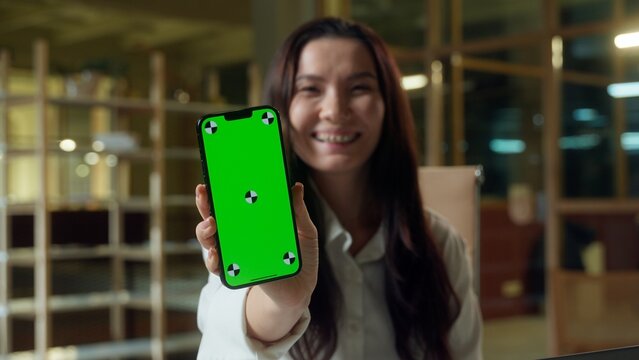 Happy business woman Asian girl browsing mobile phone green screen copy space Chinese businesswoman showing empty display chroma key Korean Japanese joyful excited female user online smartphone app - Powered by Adobe