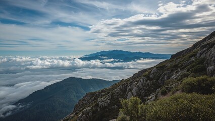 Naklejka premium High mountain peak view with clouds and valley below.