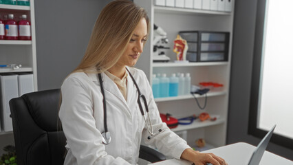 Woman doctor working at a desk in a hospital room, wearing a white coat with a stethoscope,...